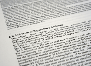 A close-up of dense government regulatory text on an official printed page, slightly out of focus in the background, with a single paragraph in sharp focus. The scene evokes the weight and volume of federal rulemaking. Cool, neutral tones — grey, off-white, black ink. Photorealistic editorial style.